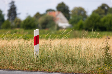 Mileage bars at the edge of the road. Picture taken on a sunny day, blurred background behind the...