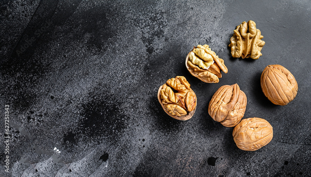 Wall mural nuts. walnut kernels and whole walnuts on dark stone table. black background. top view, flat lay wit - Wall murals