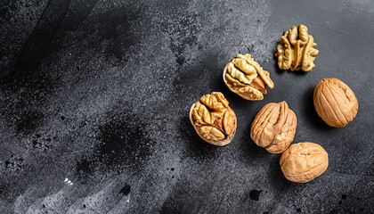 Nuts. Walnut kernels and whole walnuts on dark stone table. Black background. Top view, flat lay with copy space.