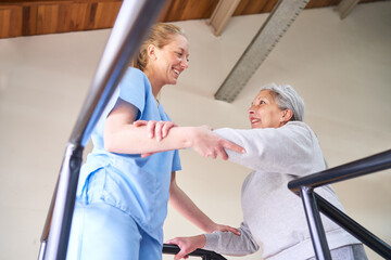 Physiotherapist assisting elderly woman in movement therapy