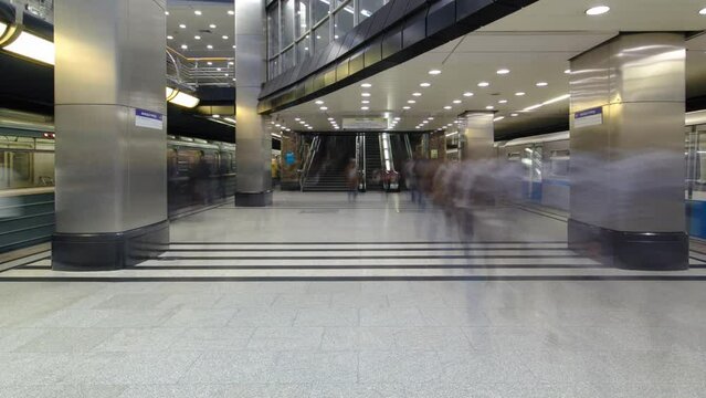 Interior of a modern subway station with trains timelapse hyperlapse. Moving backward from escalators to platform