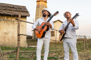 Musicians in white clothes and white hats play the guitars.