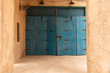 Old historic district in Dubai. Ancient arabic wooden front door in blue. Door surrounded by a clay...