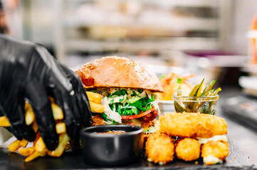 chef cooking fast food set on plate. burger, potato chips, french fries, chicken wings, fried cheese