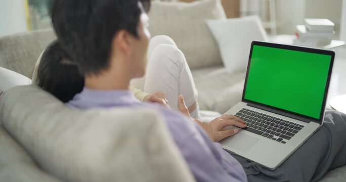녹색 목업 화면이 떠 있는 노트북을 사용하는 커플을 어깨 너머에서 본 영상