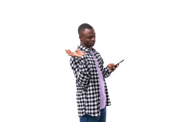 handsome young african man with short haircut in plaid shirt chatting on social network in smartphone