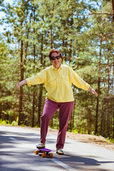 Energetic senior woman enjoying riding a skateboard. The concept of life satisfaction. Portrait of a positive gray-haired woman with a skateboard