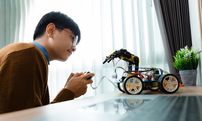 Asian teenager constructing robot arm project in house. technology of robotics programing and STEM...