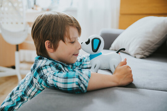 Teenage boy play with a robot dog at home