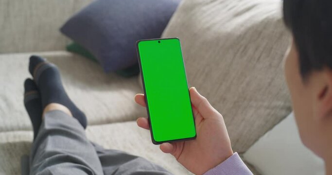 녹색 목업 화면이 떠 있는 스마트폰으로 일하는 남성을 어깨 너머로 본 영상