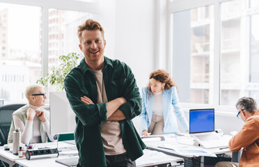 Portrait of successful mature businessman with crossed hands smiling at camera posing near office desktop, middle aged Caucasian male entrepreneur in smart casual clothes enjoying working day - Powered by Adobe