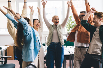 Group of diverse friends standing in office and raising arms