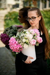 Fototapeta premium Mixed flower composition with hydrangea, peonies carnations, gypsophila in hat box in woman's hands