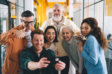 Positive multiethnic colleagues taking self shot during break in office