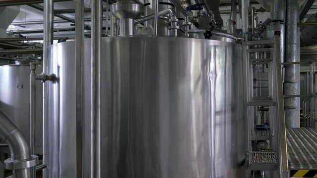 Large steel storage tanks for pasteurization of dairy products. Fermentation containers at brewery for brewing. A modern beer factory. Ice cream making cistern with barrels and pipes at food factory