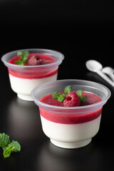 Dessert Panna Cotta with raspberries on a black background, dessert to go, delivery