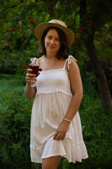 A girl in a hat holds a glass of wine on a picnic