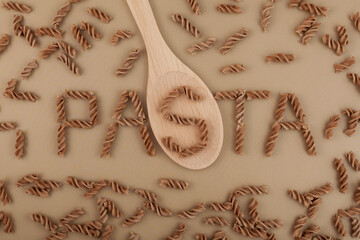 Gluten free flax pasta scattered on brown surface, top view. Design element. Uncooked Fusilli made...