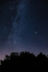Naklejka na ściany i meble Milky way stars and countryside silhouettes photographed with wide angle lens.