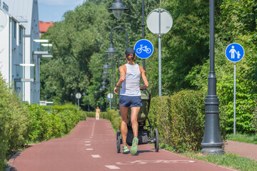 Young girl or mother running with stroller near the bike road with blue road sign or signal of...