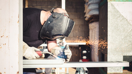 Worker wearing a protective mask welding an iron structure