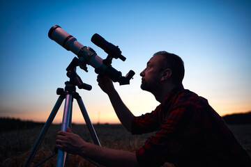 Astronomer looking at night sky with a telescope.