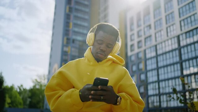 Portrait Of African American Guy Listening To Music And Singing Song On City Street, Surf Internet