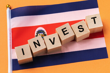 Wooden cubes with text and a flag on a colored background, a concept on the theme of investment in Costa Rica
