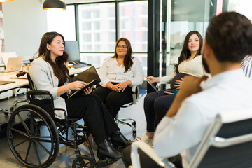 Disabled manager discussing a project with group of colleagues in office
