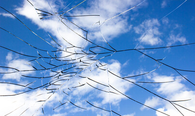 Cracks on glass.Cracked glass and sky. Damaged by impact, explosion glass.