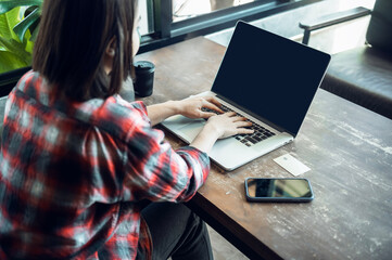 Asian woman holding plastic credit card and using laptop Online shopping concept. Tone image.