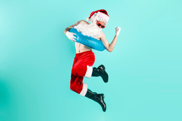santa claus in suit with inflatable swim ring in sunglasses jumps and flies and rejoices in success - obrazy, fototapety, plakaty