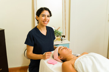 Fototapeta premium Cheerful therapist giving a skin care facial treatment