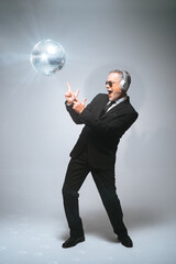 Businessman in headphones having fun with disco ball in studio