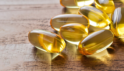 Fish oil capsules on wooden background, vitamin D supplement