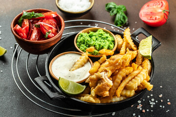 British traditional fish and potato chips served with mashed peas, vegetable salad, tartar sauce, Food recipe background. Close up