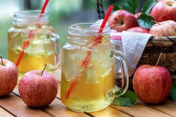 Cold apple juice with fresh apples outdoors on table