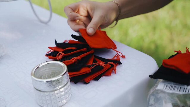 The woman puts red and black bags on the edge of the table. She is preparing for a perfume exhibition