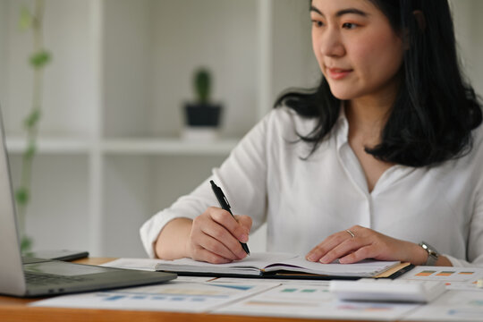 Close up image of Businesswoman take a note on report book, Business data analysis concept.