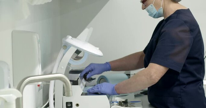 Te doctor prepares sterile packages for a medical instrument, cuts off with scissors from a roll and presses