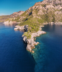 Obraz premium Rocky cliff aerial view. Azure sea or ocean coast. Summer resort and vacation destination