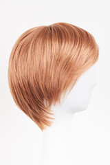 Natural looking ginger wig on white mannequin head. Short hair on the plastic wig holder isolated...