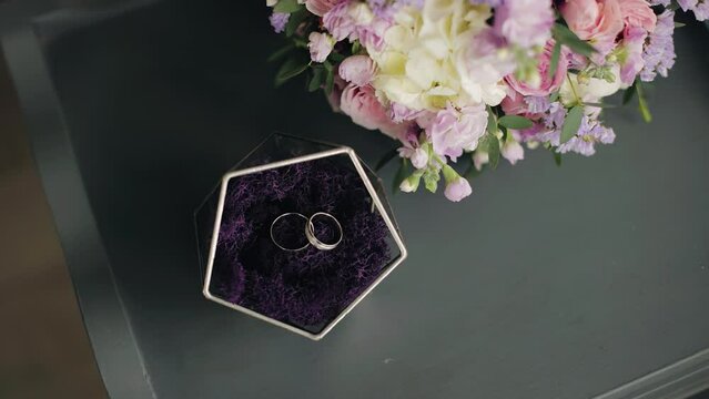 There is a box with rings on the table and a bouquet of flowers next to it. Shooting wedding accessories