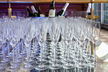 Empty glasses for champagne and wine on a table in a restaurant. Cooling bottles in a bucket with ice. Serving on a holiday at an event - 627305361