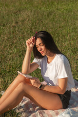 Young woman relaxing in the park and writing in a notebook