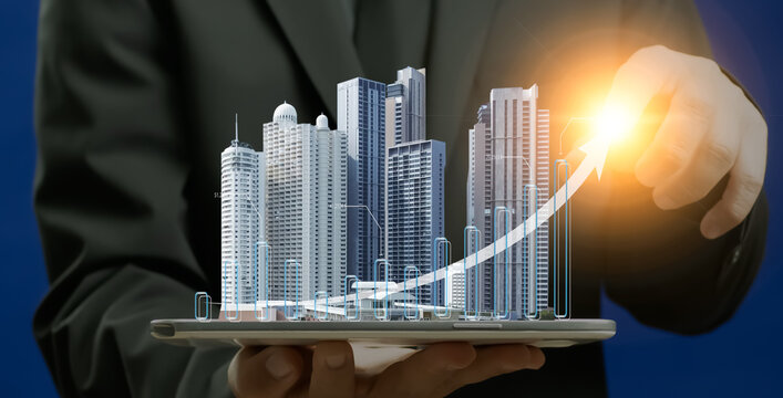 Businessman shows office building model with glowing up arrows. Finance and banking about development, investment ideas about real estate companies, financial success and growth concept.