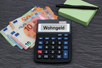 Display eines Taschenrechners mit dem Wort  Wohngeld und Euro Banknoten. - obrazy, fototapety, plakaty