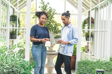 bearded Thai husband and his African American wife help plant trees and water the nursery in the backyard.