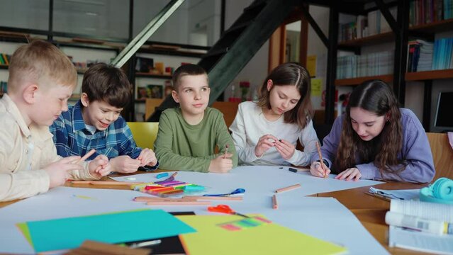 Cheerful children drawing with pencils and talking at library