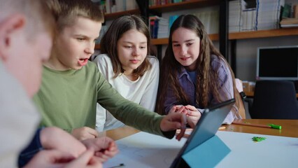 Handsome teenage boys and girls watching video on tablet at drawing table at library - Powered by Adobe